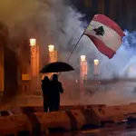 Dos manifestantes ondean la bandera de Líbano bajo el amparo de un paragüas en Beirut. EFE/EPA/WAEL HAMZEH