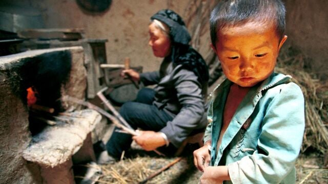 FILE--A young boy waits as his grandmother prepares a fire for cooking, in their mud-walled house in Jiaotu Village, in Yinhe County, in China's western Qinghai province in this August 3, 1999 file photo. An independant assessment panel has said that the World Bank failed to properly assess the environmental and social impact of a $40 million project to resettle 58,000 impoverished families from the area to another part of Qinghai inhabited by Tibetans. The panel, in a 160 page report, claimed the World Bank did not adequately consult with the 4,000 Tibetan and Mongol herders who live in the resettlement area. (AP Photo/Greg Baker)