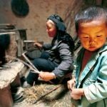 FILE--A young boy waits as his grandmother prepares a fire for cooking, in their mud-walled house in Jiaotu Village, in Yinhe County, in China's western Qinghai province in this August 3, 1999 file photo. An independant assessment panel has said that the World Bank failed to properly assess the environmental and social impact of a $40 million project to resettle 58,000 impoverished families from the area to another part of Qinghai inhabited by Tibetans. The panel, in a 160 page report, claimed the World Bank did not adequately consult with the 4,000 Tibetan and Mongol herders who live in the resettlement area. (AP Photo/Greg Baker)