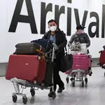 Viajeros con mascarillas llegan al aeropuerto de Heathrow en Londres