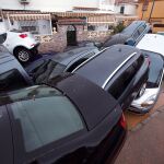 Coches amontonados frente a una casa este sábado en el distrito de Campanillas, Málaga, tras desbordarse un río por las fuertes lluvias de esta madrugada