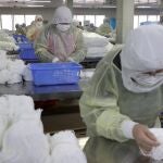 Varias personas trabajan en una fábrica de mascarillas este lunes en Nantong (China).