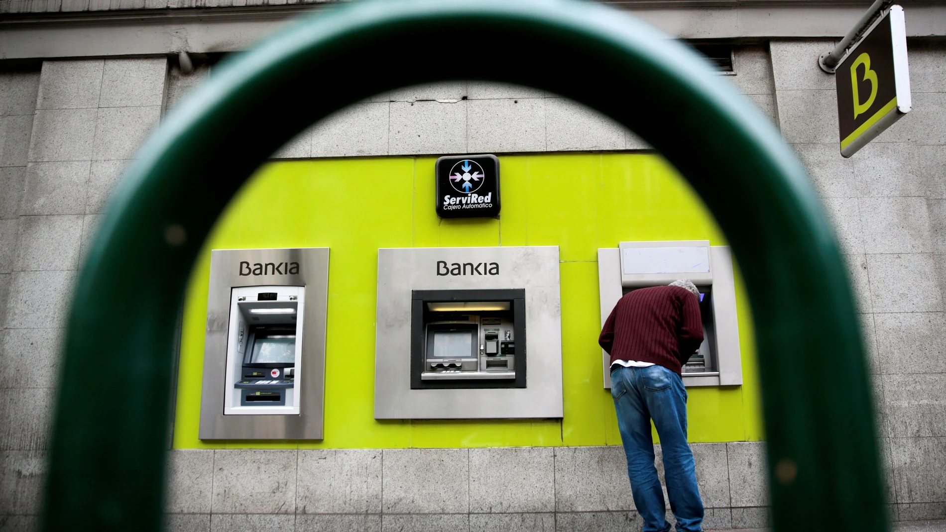 FILE PHOTO: A man uses a cash dispenser at a Bankia branch in Madrid