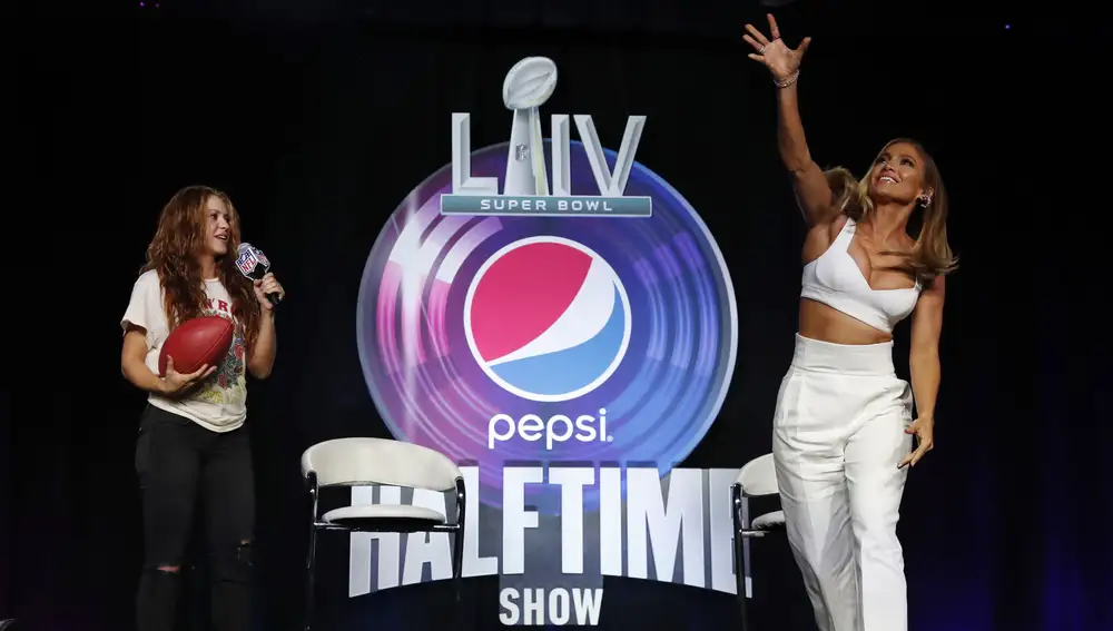 La cantante estadounidense Jennifer Lopez (d) lanza un balón de fútbol americano durante una rueda de prensa con la cantante colombiana Shakira (d) sobre el espectáculo del medio tiempo del LIV Super Bowl en Miami, Florida (EE. UU.). EFE/ John G. Mabanglo