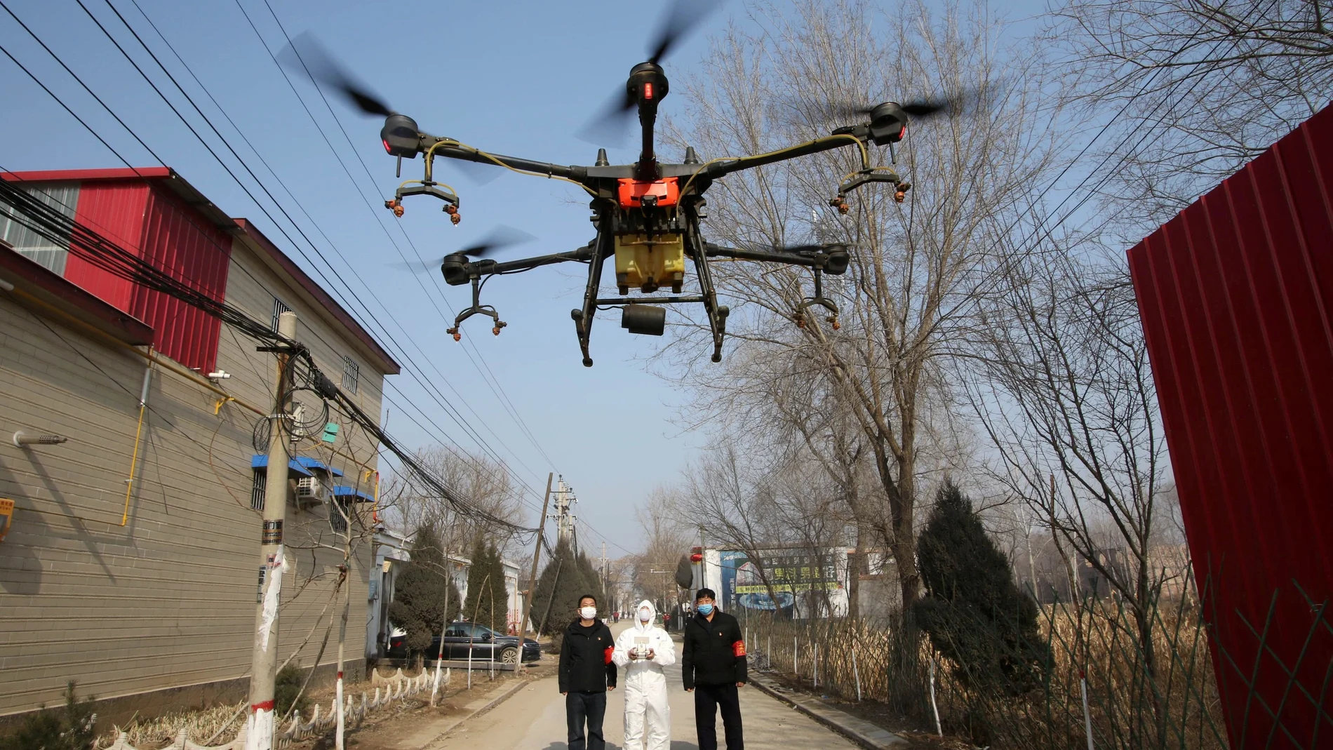 Volunteer in protective suits controls a drone to spray disinfectants at Zhengwan village, as the country is hit by an outbreak of the new coronavirus, in Handan