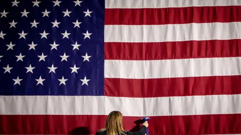 Imagen de una asistente planchando la bandera estadounidense en el Caucus de Iowa (EE.UU).