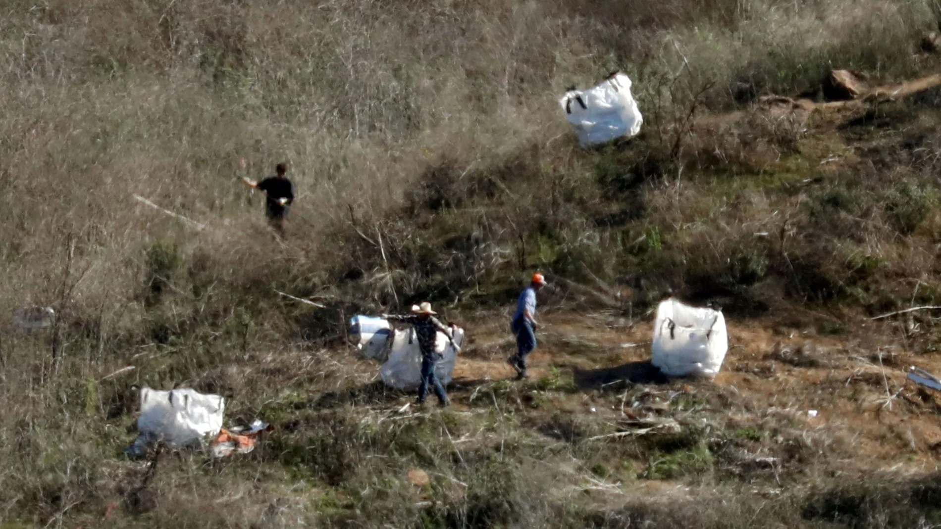 FILE PHOTO: Personnel collect debris while working with investigators at the helicopter crash site of NBA star Kobe Bryant in Calabasas, California