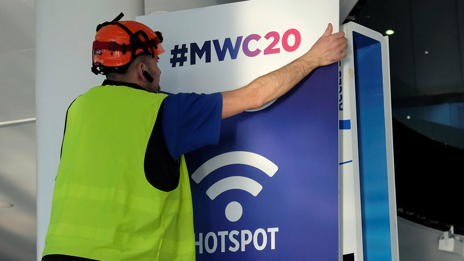 An employee places a banner with information of MWC20 in Barcelona