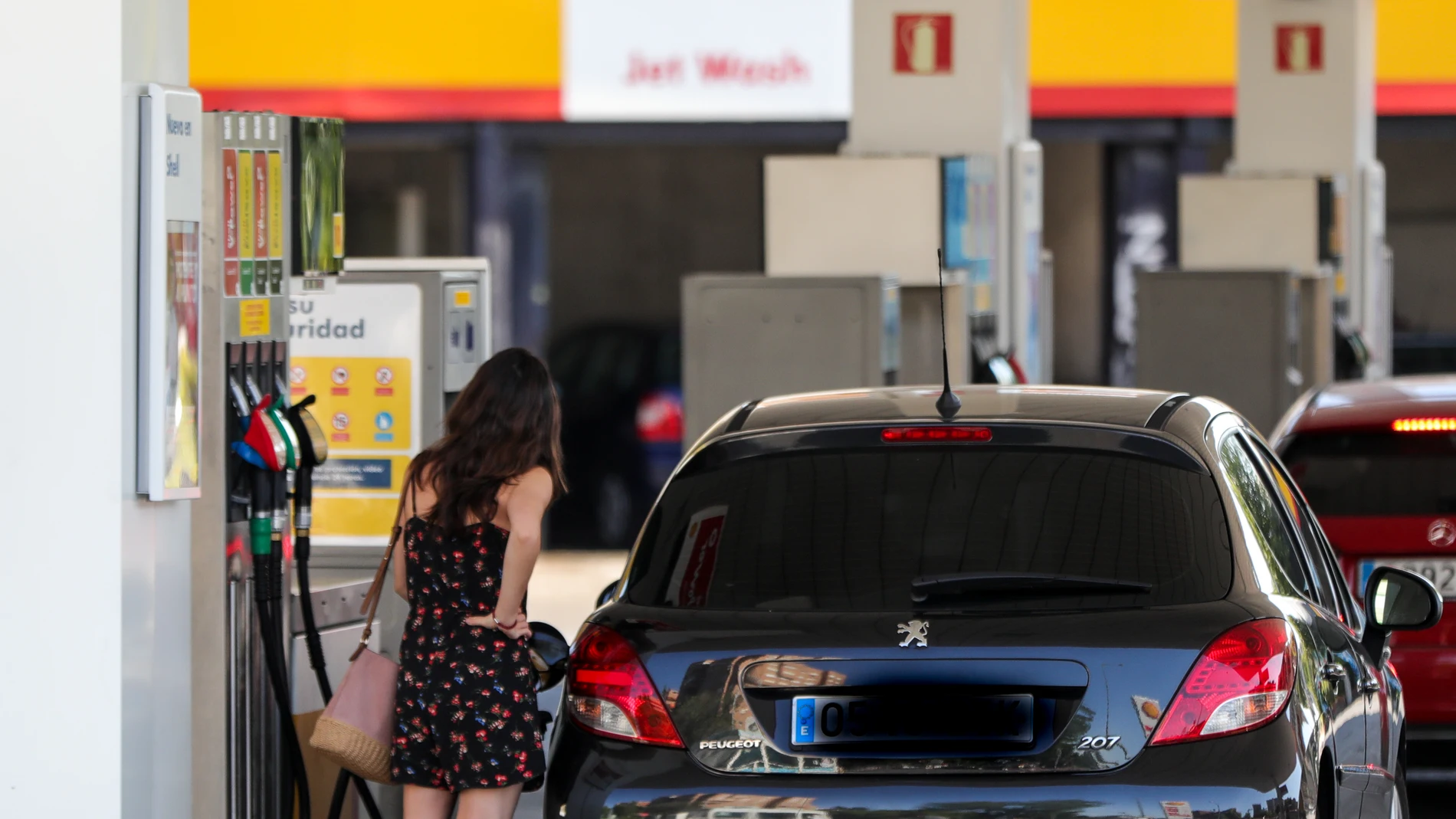 Personas ponen gasolina en sus coches en una gasolinera