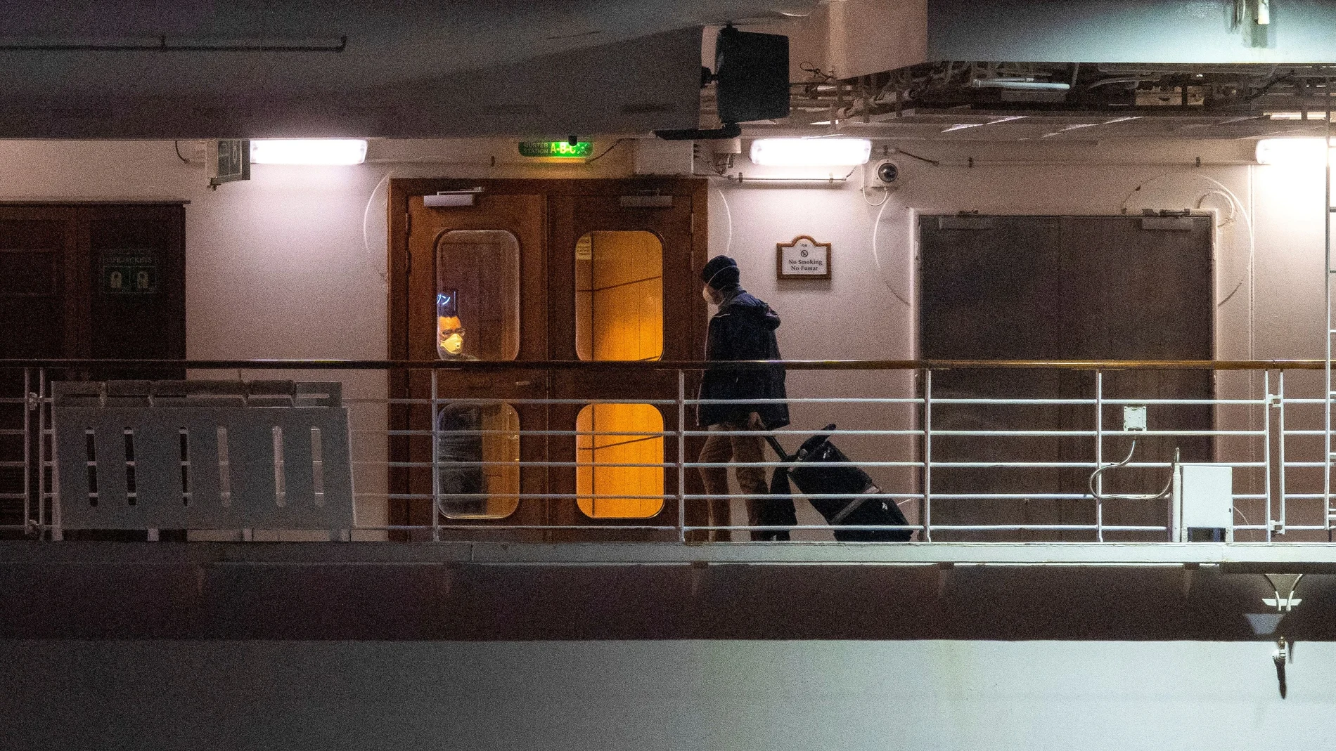 A passenger with his belongings is seen before the evacuation of the U.S. passengers of the Diamond Princess cruise ship, where dozens of passengers tested positive for coronavirus, as they arrive at Daikoku Pier Cruise Terminal in Yokohama