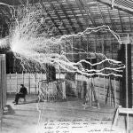 Nikola sentado al lado de una bobina de Tesla, en su laboratorio de Colorado Springs (1899)
