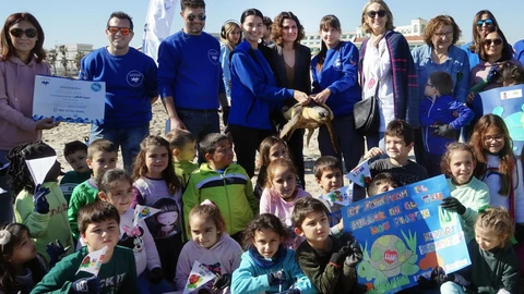 Un grupo de escolares participa en una suelta de tortugas en la playa de Las Arenas