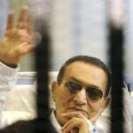Hosni Mubarak saluda a sus seguidores tras los barrotes en una vista de su juicio