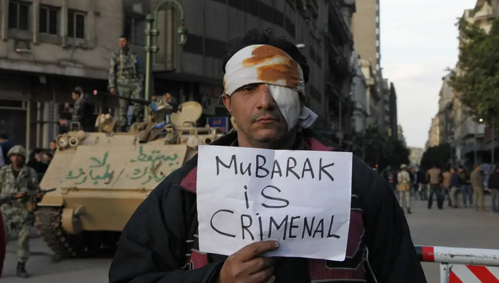 Imagen de 2011 en la que un manifestante herido porta un cartel en el que se puede leer &quot;Mubarak es un criminal&quot;