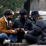 Varias personas con máscaras protectores revisan sus teléfonos móviles este martes en Milán (Italia).