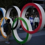 People wait in line to take pictures with the Olympic rings near the New National Stadium, Sunday, Feb. 23, 2020, in Tokyo. (AP Photo/Jae C. Hong)