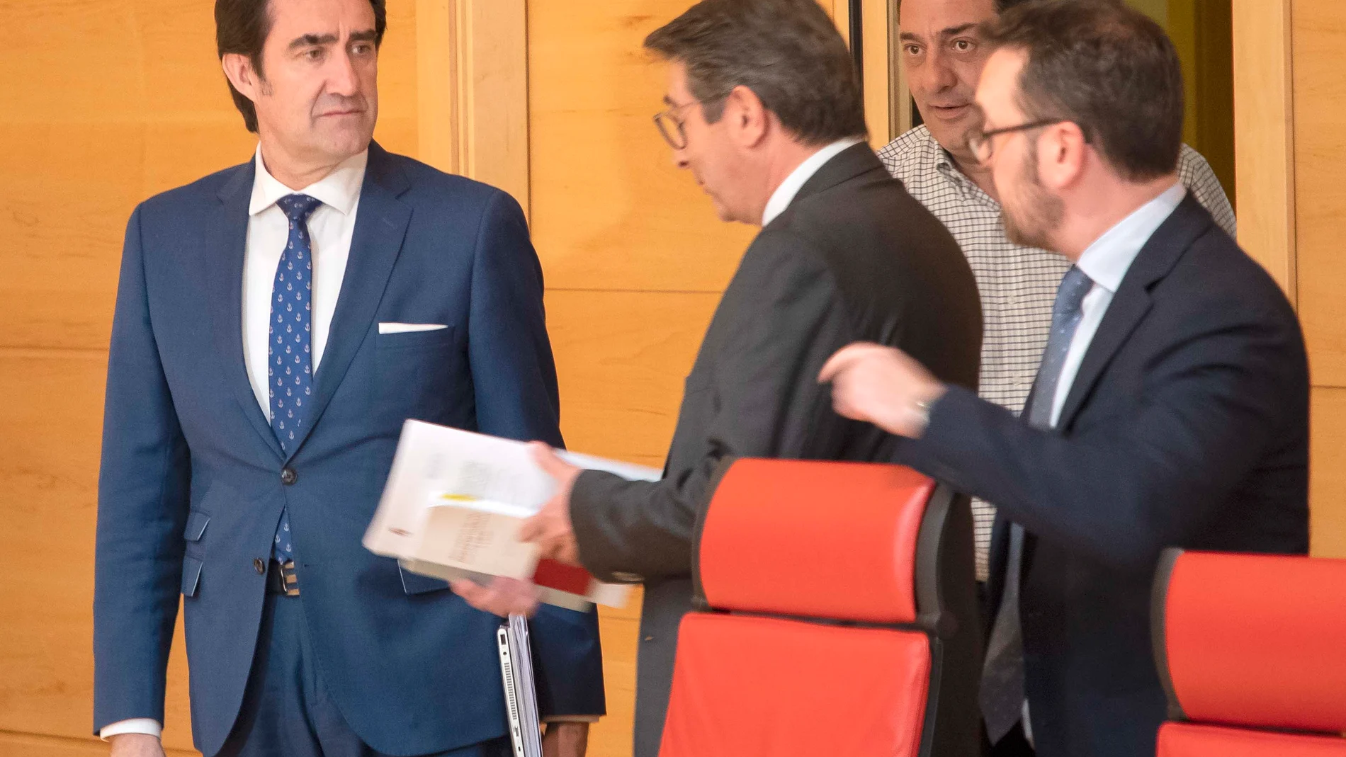 El consejero de Fomento y Medio Ambiente, Juan Carlos Suárez-Quiñones, dialoga con varios procuradores momentos antes de comparecer en las Cortes