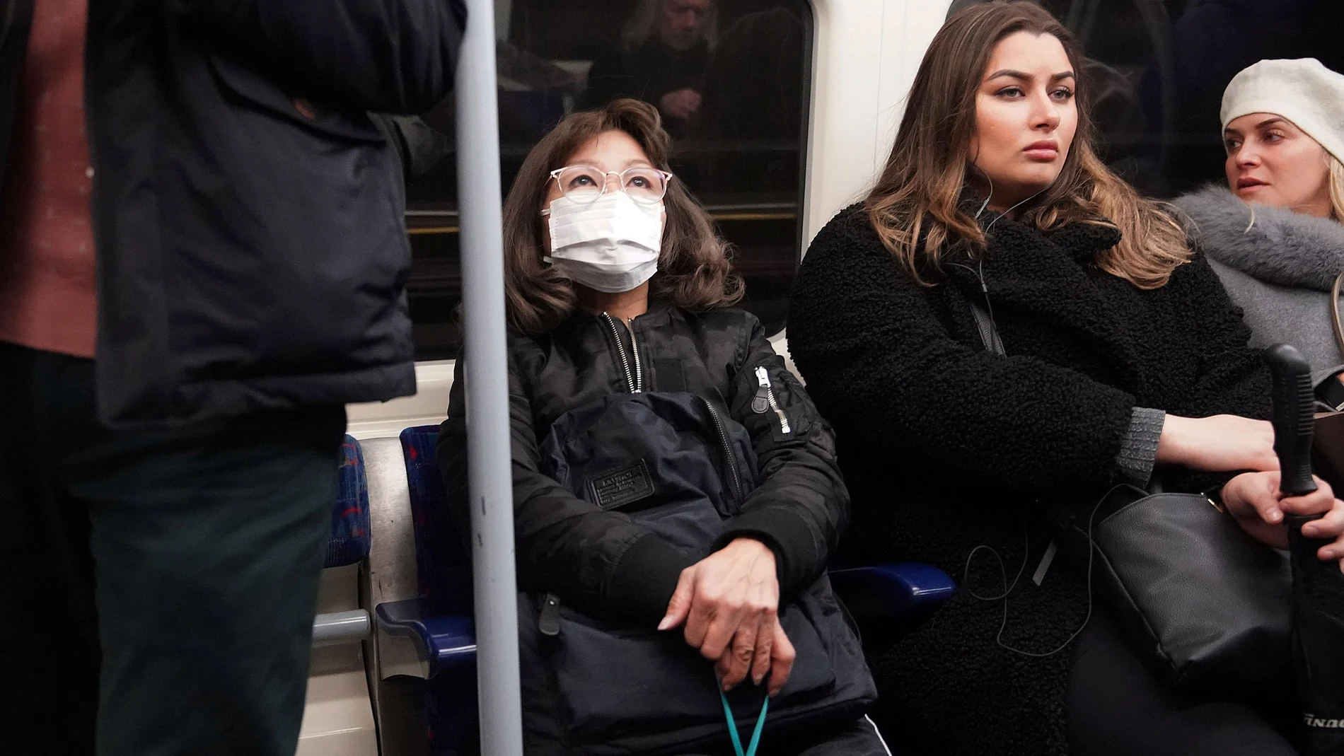 A woman wearing a protective mask travels on a Jubilee Line tube train in London