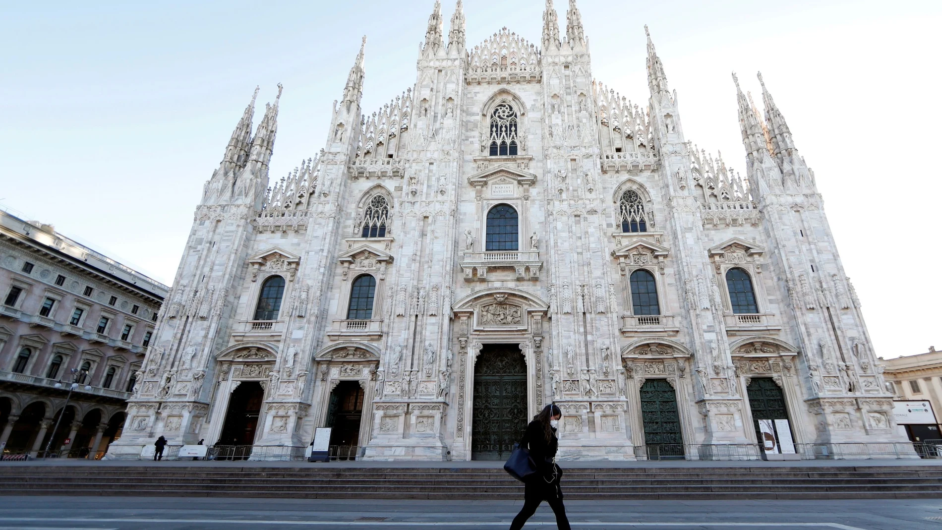 A woman wearing a protective face mask walks through Duomo square, as a coronavirus outbreak continues to grow in northern Italy, in Milan