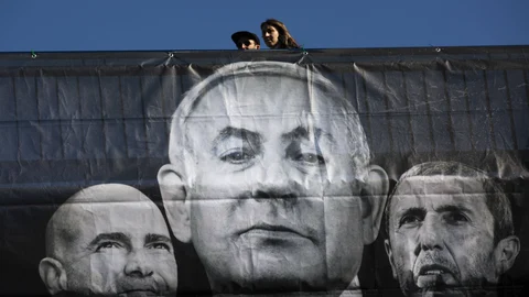Una pareja camina sobre un cartel electoral del partido Azul y Blanco con las imagen central de Netanyahu. (AP Photo/Oded Balilty)