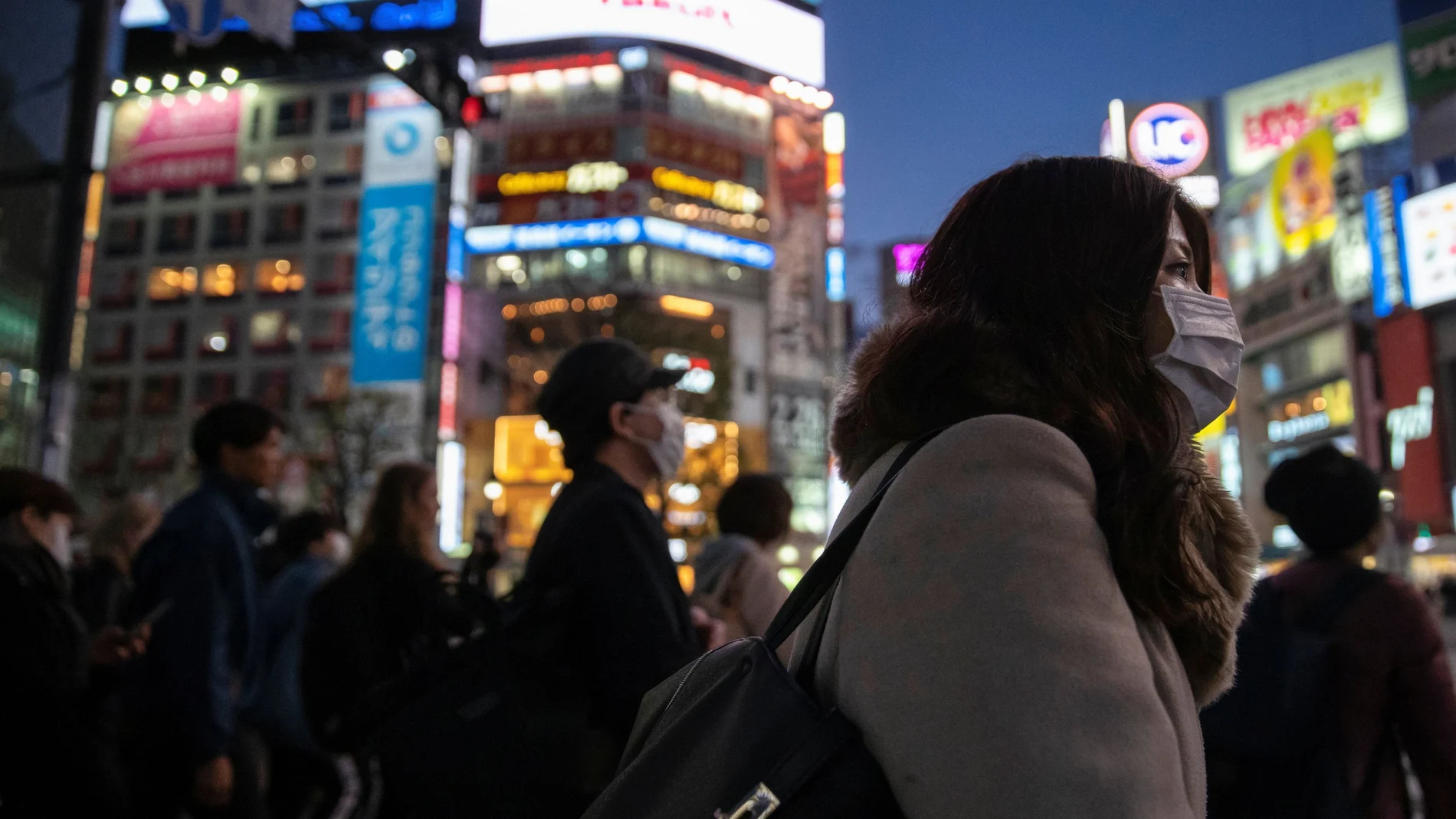 A woman wearing a protective mask is seen at the scramble crossing in Shibuya shopping district, also known as Shibuya crossing, following the outbreak of the coronavirus in Tokyo