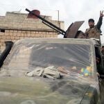 Soldados sirios hacen el gesto de la victoria en una población al sur de la provincia de Idlib