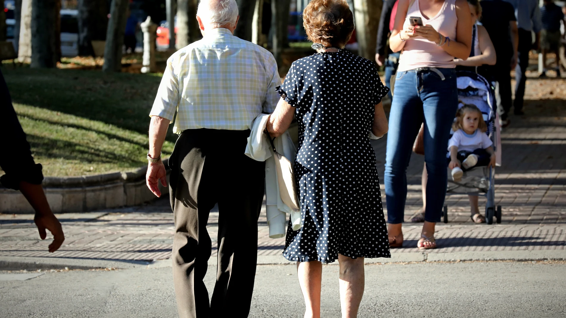 Una pareja de ancianos pasea por un municipio madrileño.