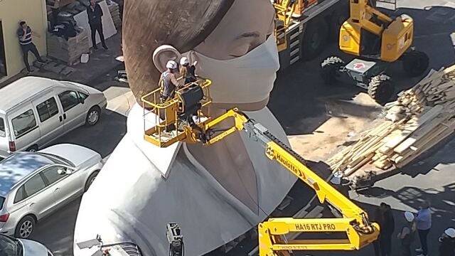 Los artistas de la falla municipal, con la "plantà" detenida, provecharon para ponerle una mascarilla a la figura principal.