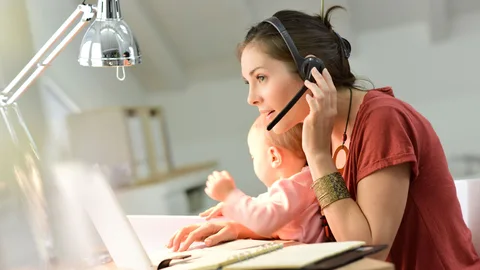 Una madre teletrabja con su bebé en brazos