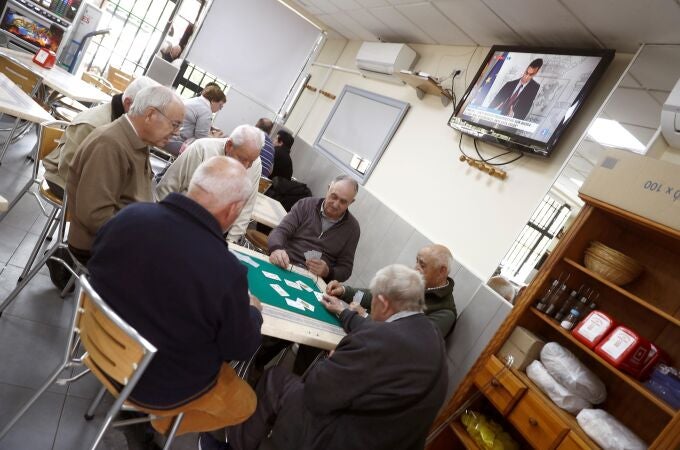 Un grupo de ancianos juega al mus en un bar del barrio de Aluche, en Madrid
