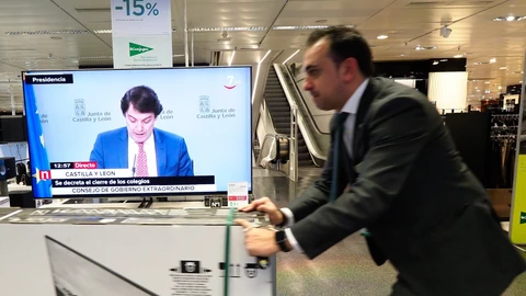 Un dependiente se prepara para cerrar con el presidente de la Junta de Castilla y León, Alfonso Fernández Mañueco, en las televisiones a la venta, anunciando la suspensión de clases en toda la Comunidad