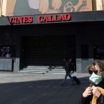 Una mujer camina protegida con una mascarilla junto a los cines Callao en Madrid, este viernes.