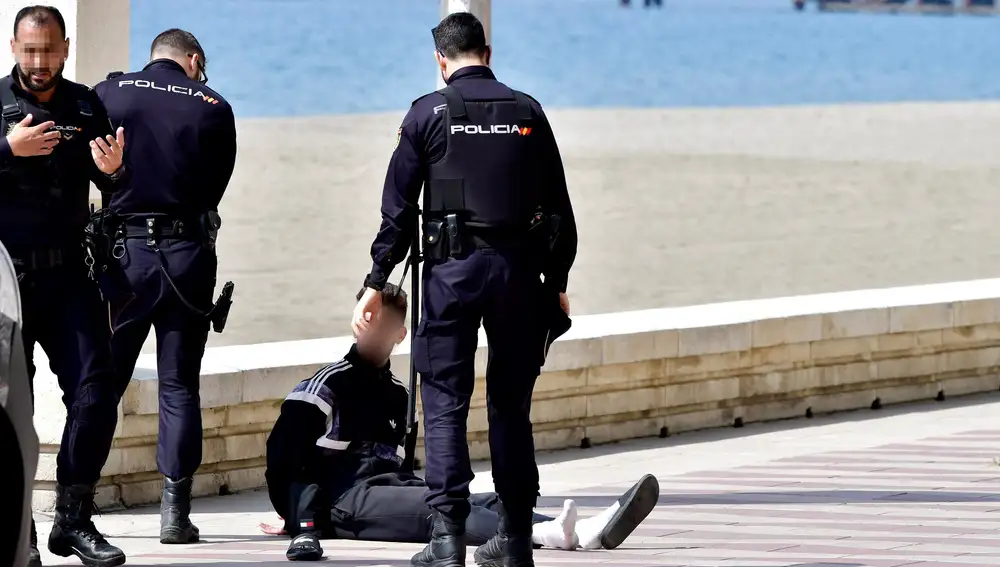 Miembros del Cuerpo Nacional de la Policía detienen a un ciclista en el Paseo Marítimo de Almería, donde han estado instando a los viandantes a cumplir las medidas de contención por el coronavirus