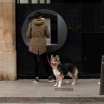 Una mujer saca dinero de un cajero y pasea a su perro en Barcelona