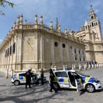 Policías junto a la Catedral de Sevilla, alejada de su bullicio habitual por la cuarentena establecida por el Gobierno