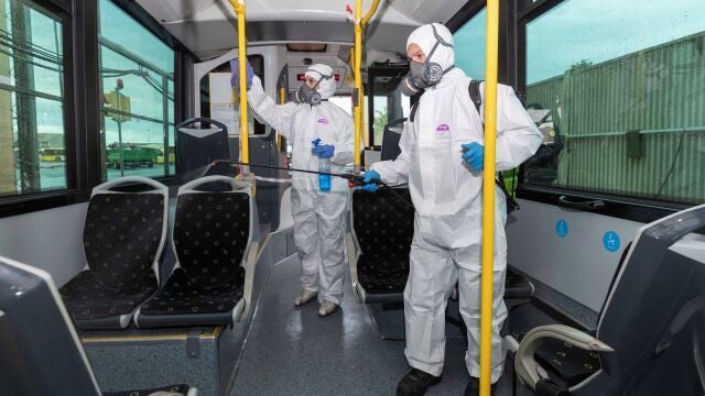 Dos trabajadores de una empresa de limpieza especializada desinfectan un autobús urbano de Murcia