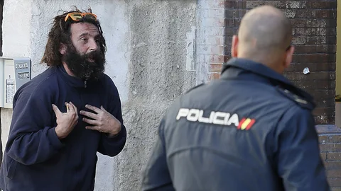 Un agente de la Policía Nacional conmina, junto a la Catedral de Sevilla, a una persona indigente a que abandone su estancia en la calle