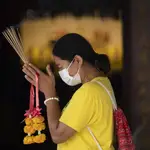 Una mujer con mascarilla hace sus plegarias en el templo de Leng Nuei Yee en Bangkok, este lunes