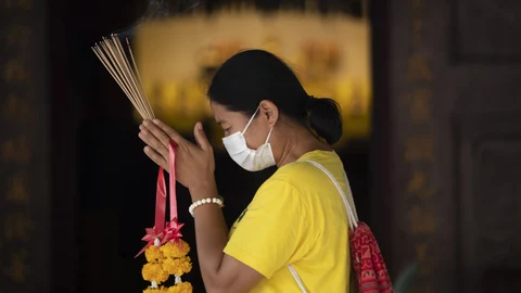 Una mujer con mascarilla hace sus plegarias en el templo de Leng Nuei Yee en Bangkok, este lunes