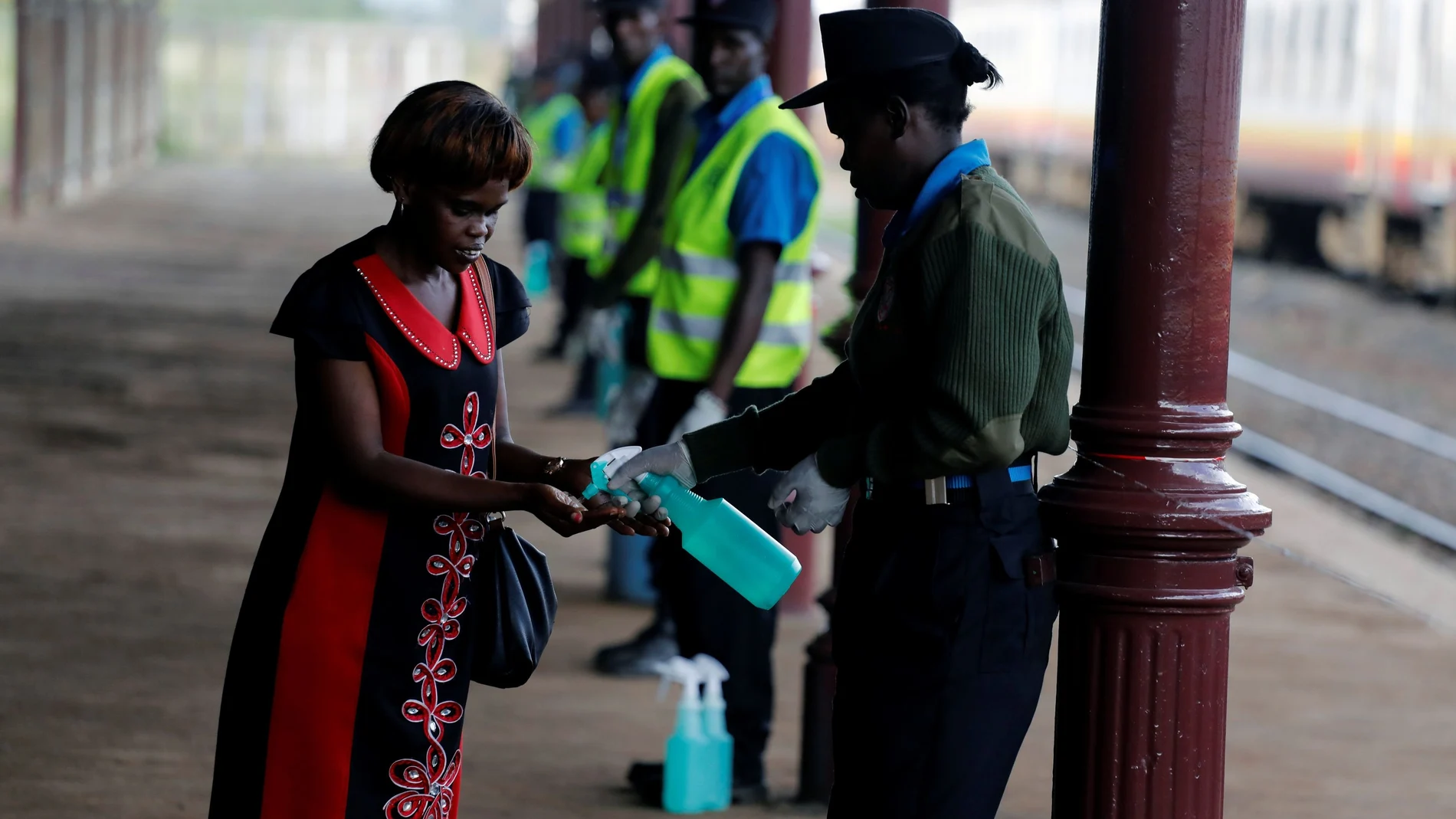 A security guard uses a sprayer to sanitise a commuter hands before she boards a train to prevent the spread of coronavirus disease (COVID-19), at the main railway station in Nairobi