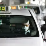 Un taxista con mascarilla espera en el aeropuerto de Madrid,