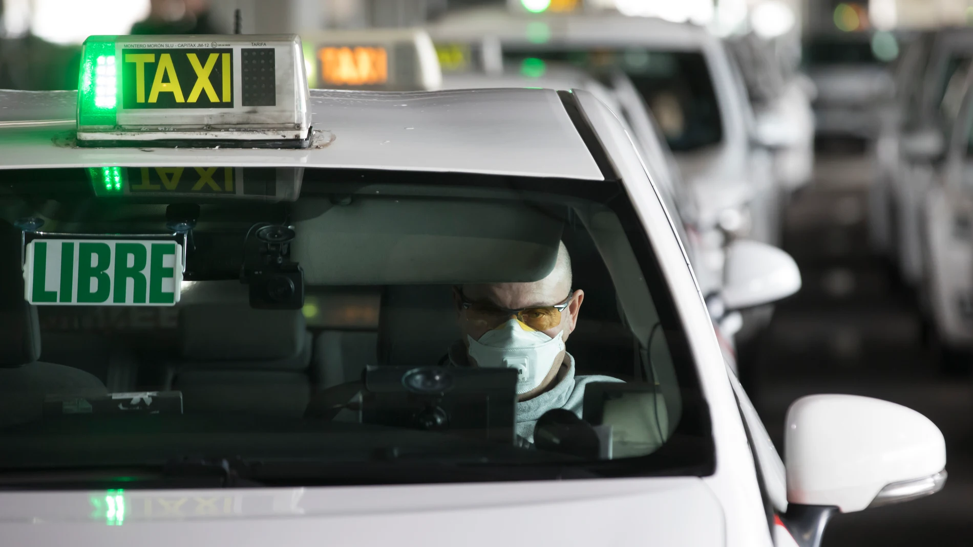 Un taxista con mascarilla espera en el aeropuerto de Madrid