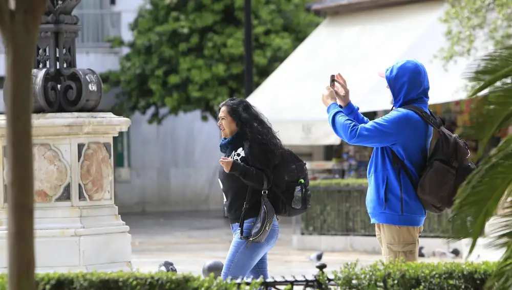 Unos turistas hacen fotos en una céntrica plaza de Sevilla