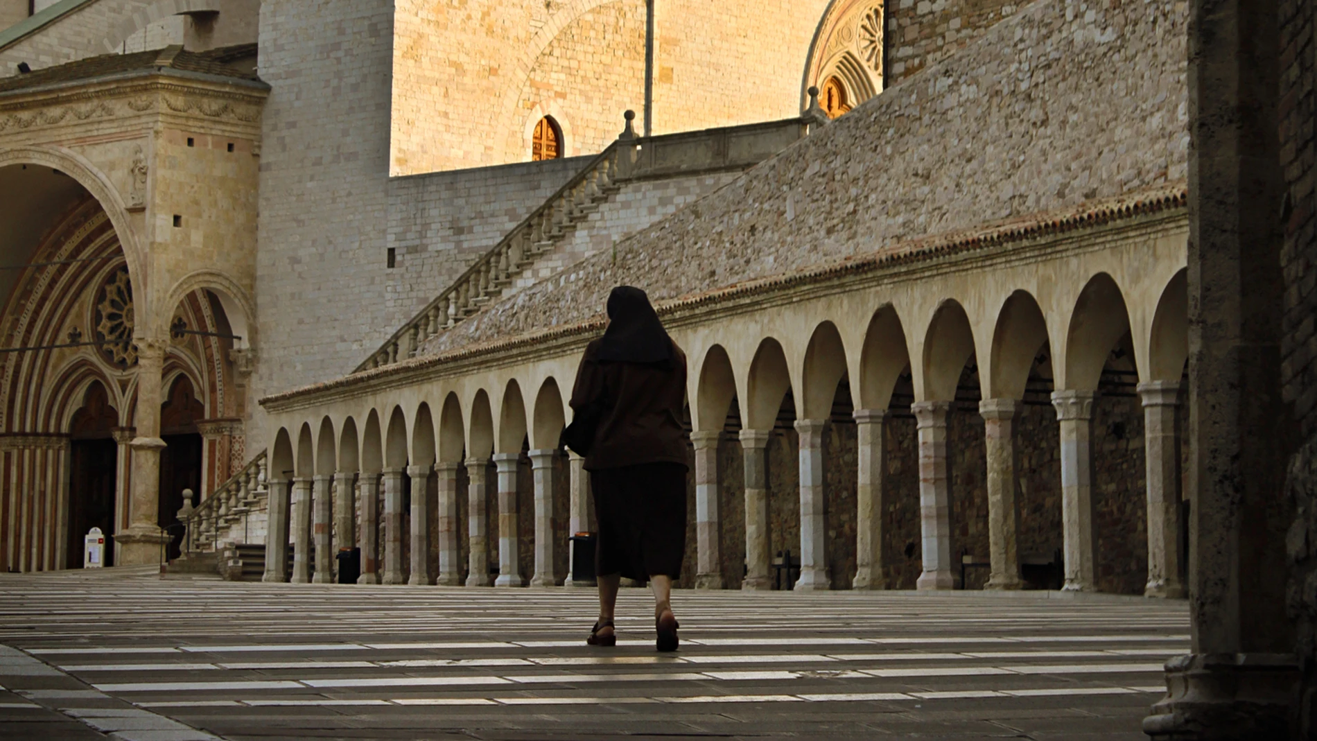 Una monja que camina hacia la entrada de St Francis de la basílica de Assisi