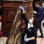 Una trabajadora de la limpieza desinfecta la barandilla del Congreso, este miércoles en el Congreso, durante una de las intervenciónes del presidente del Gobierno, Pedro Sánchez, para explicar la declaración del estado de alarma.