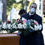 Un empleado del cementerio de Bérgamo se protege con una mascarilla/REUTERS