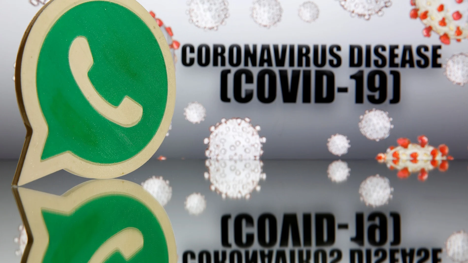 A 3D-printed Whatsapp logo is seen in front of displayed coronavirus disease (COVID-19) sign