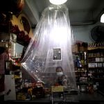 Una cajera del supermercado atiende a los clientes protegida por unas cortinas de plástico por coronavirus en Buenos Aires