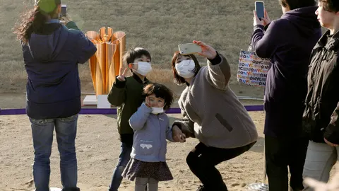 Una familia se hace une selfie con la llama olímpica en Ishinomaki, en la región de Higashimatsushima, al norte de Japan