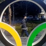 Un policía protegido por una máscara para evitar posibles contagios pasea junto a los anillos olímpicos instalados en Tokio